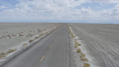 car driving fast on desert open road, aerial backward flight