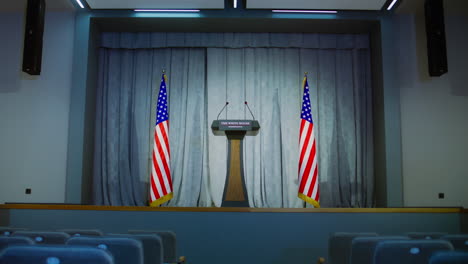 Speech-tribune-for-US-President-or-government-representative-in-the-White-House.-Press-conference-hall-with-seats.-Wooden-podium-debate-stand-with-microphones-on-stage.-Backdrop-with-American-flags.