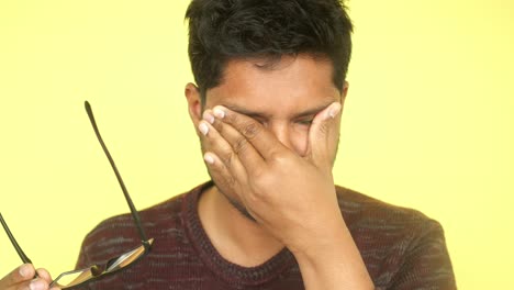 man rubbing his eye, looking tired