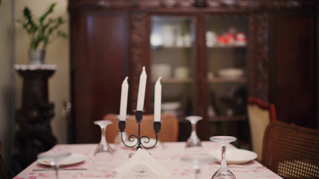 Dining table set with plates, glasses, and white candles in a cozy home interior