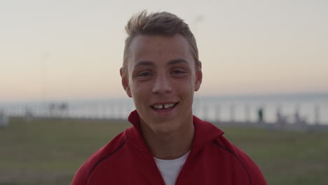 close up portrait confident teenage boy puts on helmet smiling enjoying relaxed summer vacation on seaside park at sunset slow motion