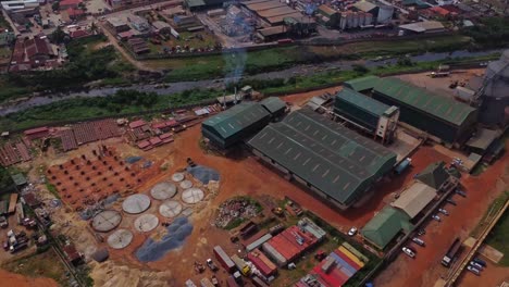 aerial of large factory plant next to a river with smoke coming from the chimneys in ibadan, nigeria