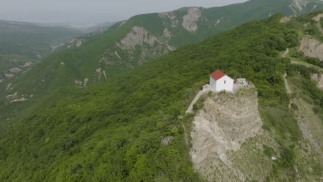 High-angle-aerial-shot-of-a-small-building-surrounded-with-forested-hills
