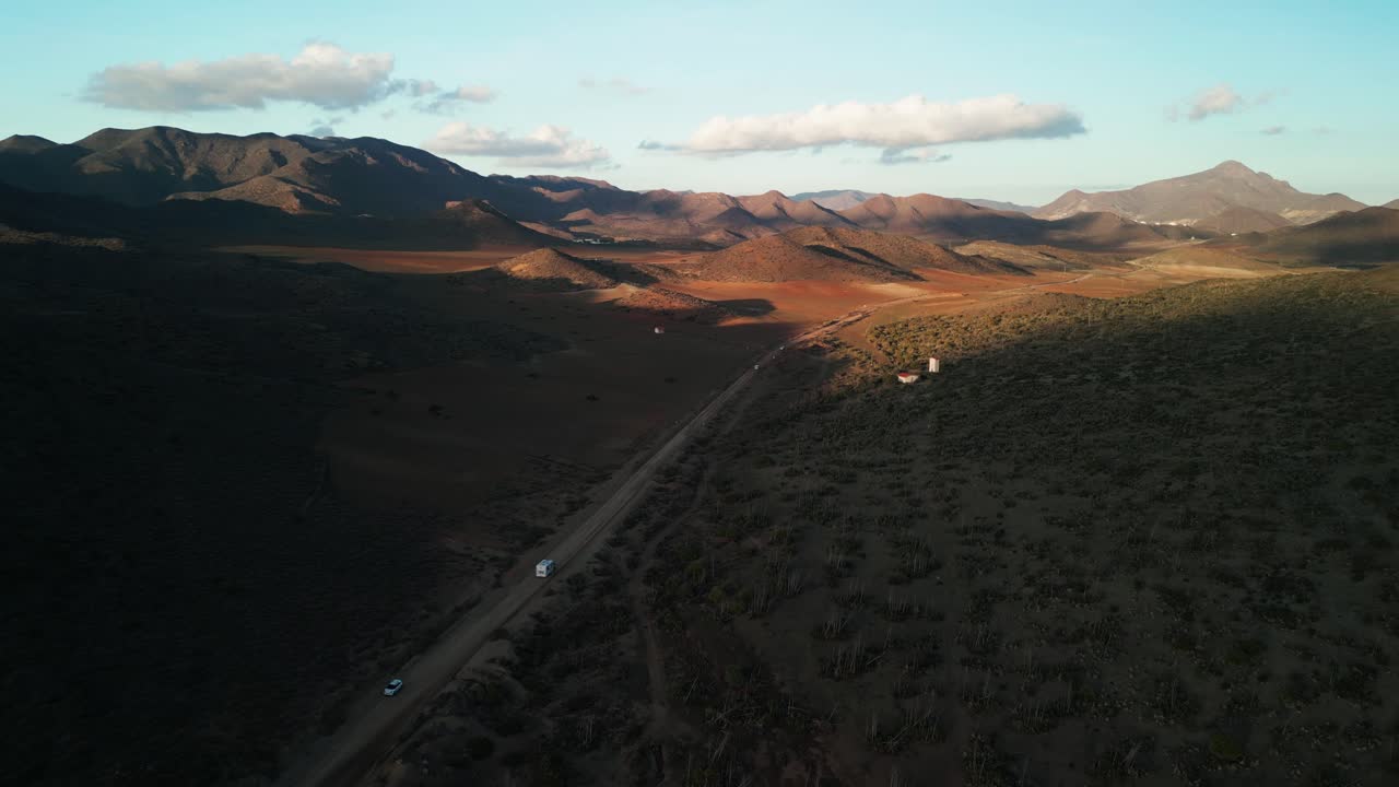 Vista aerea di veicoli che attraversano un vasto paesaggio montuoso desertico