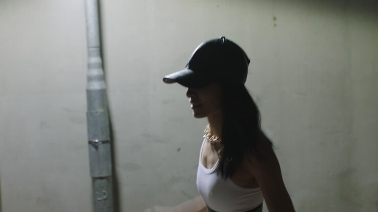 donna danzante giovane ballerina di strada donna che pratica movimenti di danza moderna freestyle in città di notte indossando un cappello