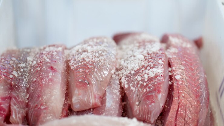 Person Adding Salt On Raw Herring Fish To Make Soused Herring. - closeup shot