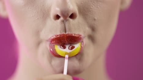 chica lamendo helado con seducción, boca en primer plano en fondo rosado