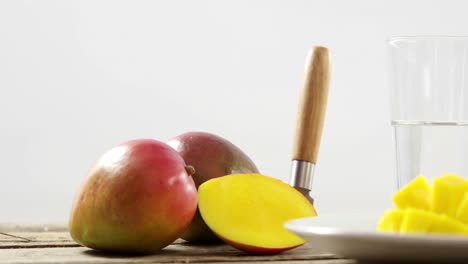 mango cortado por la mitad y picado con un cuchillo en una mesa de madera