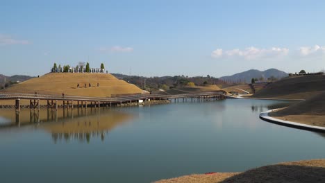 Viajeros-Caminando-Por-Senderos-En-Espiral-De-La-Colina-Bonghwa-Y-El-Puente-De-Los-Sueños-En-El-Jardín-Del-Lago-De-La-Bahía-De-Suncheonman,-Ciudad-De-Suncheon,-Jeonnam,-Corea-Del-Sur