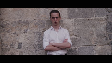 young man leaning against a stone wall