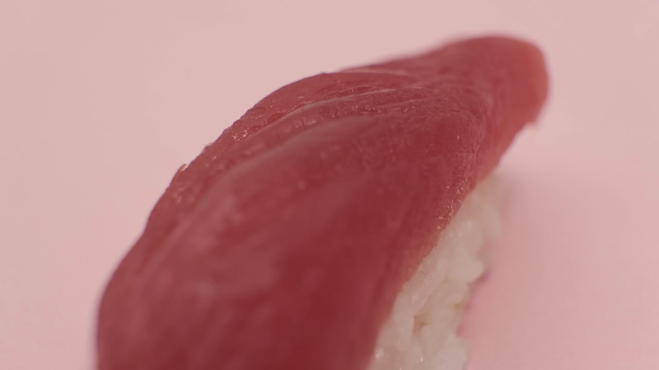 un rollo de sushi girando sobre un fondo rosado