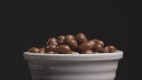 sliding shot approaching bowl of chocolate covered peanuts