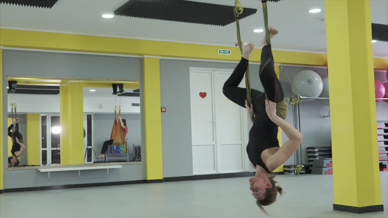 Woman practicing aerial yoga in a gym