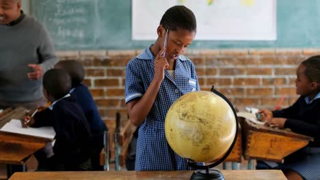 schoolgirl using globe in classroom 4k