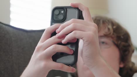 tight shot of young man on phone sitting on a couch, man is out of focus, texting