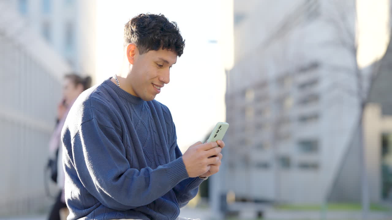 Young latin man using smartphone in urban setting