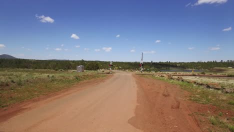 una antena de cruces de caminos de tierra sobre las luces de advertencia de las vías del tren parpadean en rojo para el tráfico de trenes que se aproxima, cerca de williams, arizona
