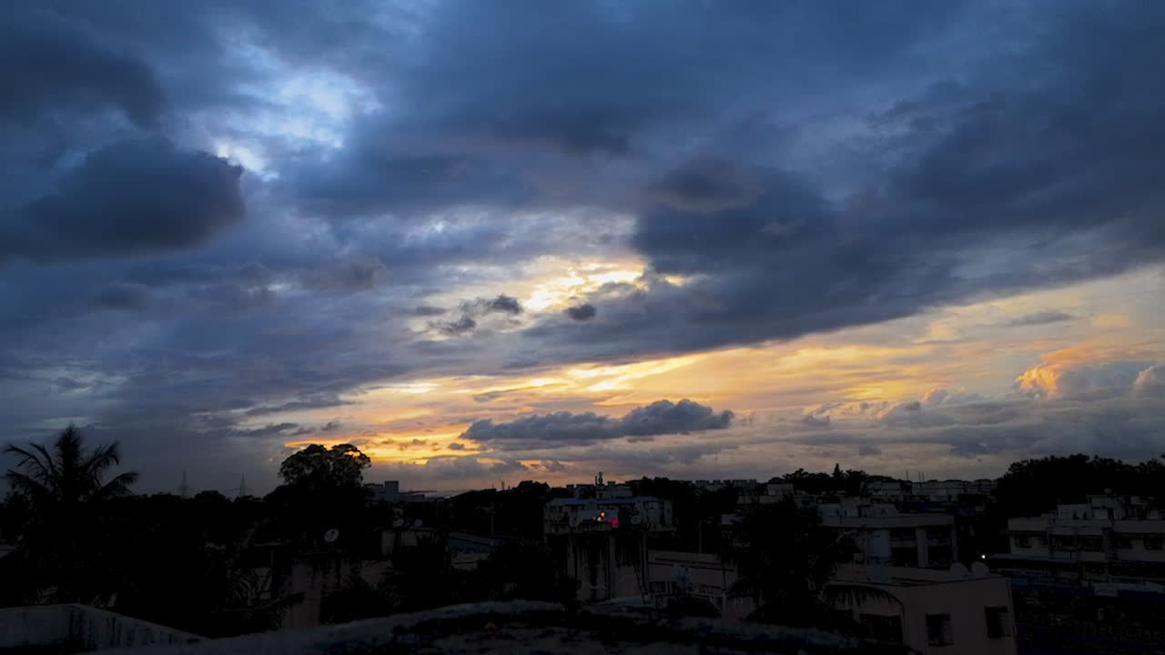 timelapse dramático de la puesta de sol sobre una ciudad con nubes en el cielo y tonos naranjas