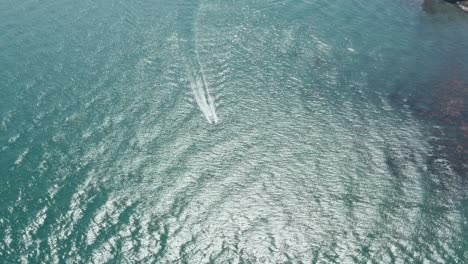 overhead-pan-down-drone-shot-of-small-speed-boat-in-a-blue-sea