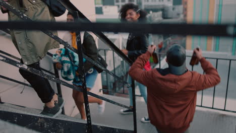 group of young multiracial friends walking up fire escape stairs ready for rooftop party chatting sharing excitement for weekend celebration