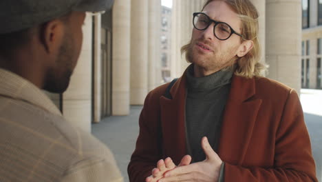 handsome businessman speaking with colleague outdoors in city