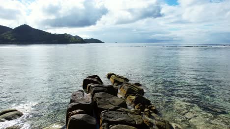 Mahe-Seychelles-Rocks-reveal-on-the-beach,-moving-forward-with-drone-to-spot-rock-formations