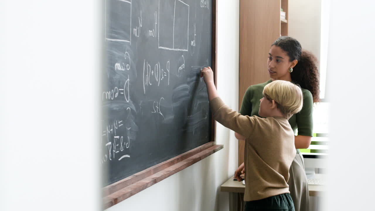 Student and Teacher Working on Math Problems on a Blackboard