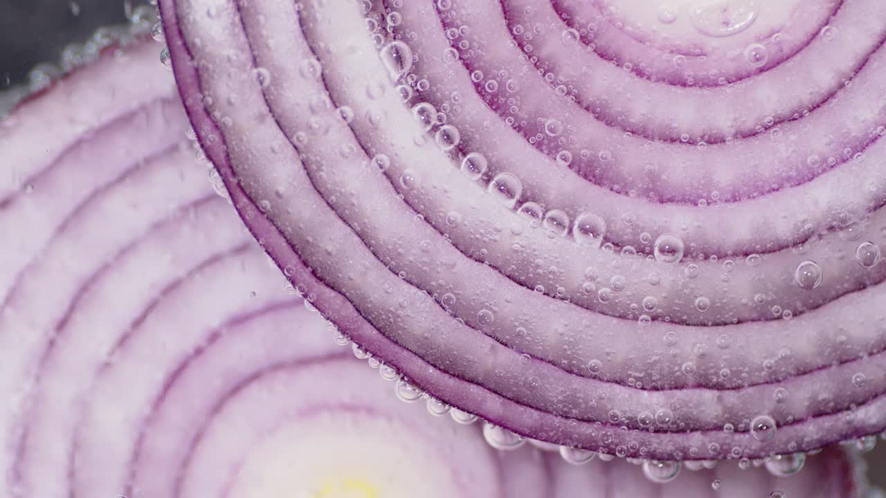Rings of red onions under water with air bubbles.