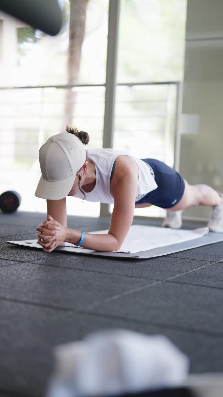atleta femenina sostiene la tabla como ejercicio abdominal en un gimnasio cubierto, españa