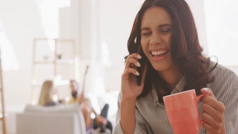 mujer hablando en el teléfono inteligente mientras sostiene una taza de café