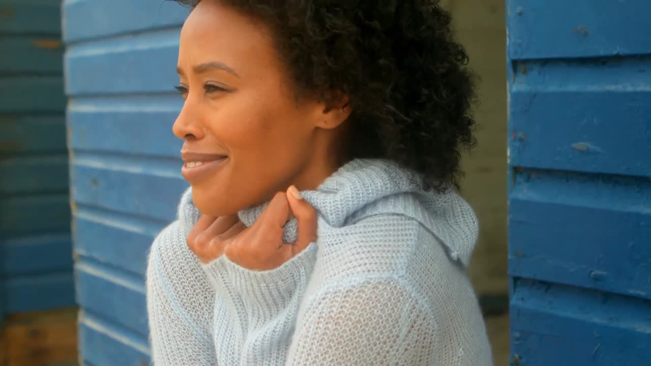 Young African american woman shivering while standing on beach hut 4k