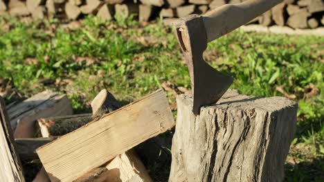 hacha metida en un tronco de madera con una pila de leña cortada, deslizador