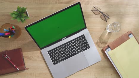 portátil en un escritorio de madera con pantalla verde