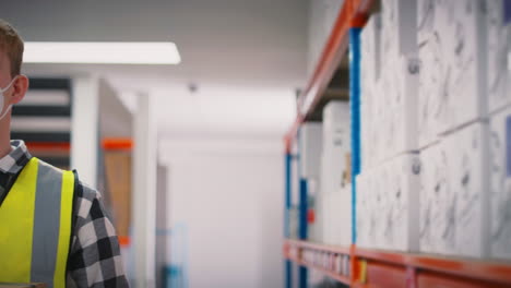 retrato de un trabajador masculino con máscara facial de ppe sosteniendo una caja dentro del almacén