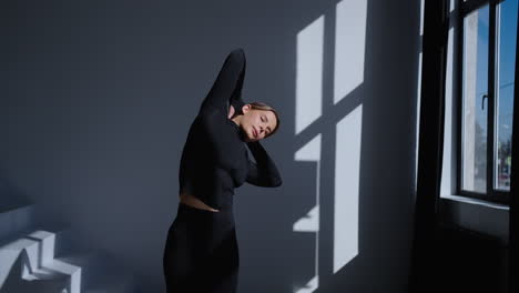 woman in black workout outfit stretching in studio