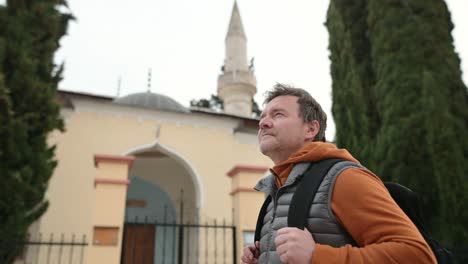 mature tourist enjoy a stroll through the old town of trebinje, bosnia and herzegovina. backpacker examines the facade of osman pasha mosque