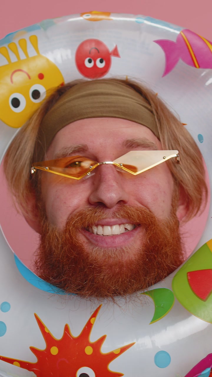 Funny young hippie tourist man looking out of rubber swimming ring summer vacation time sea travel