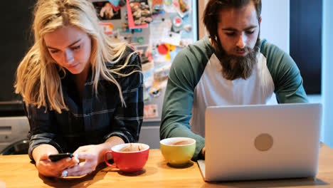 Couple-using-laptop-and-mobile-phone-in-kitchen-4k