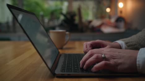 a close-up of hands typing on a laptop in a warm home setting. the screen displays an ai chatbot used for financial planning. soft lighting, cozy kitchen background, and coffee cup.