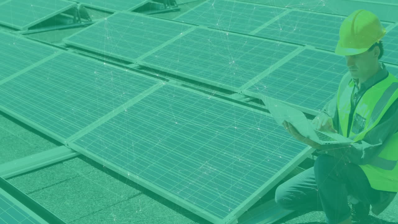Man kneeling on rooftop solar panels, typing on laptop showing solar technology data network