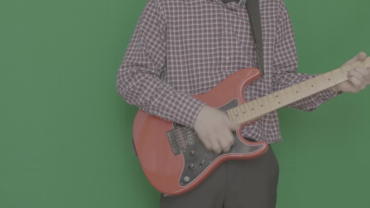 A man plays an electric guitar on a Green Screen.