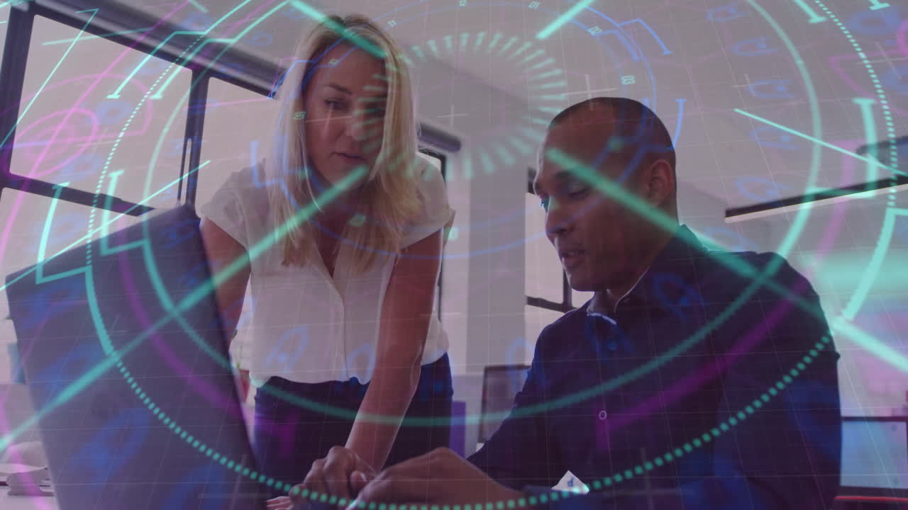 Woman leaning over laptop and man pointing, presenting tech data with HUD graphics in office