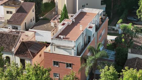 an aerial view of a spanish residential area, showcasing a mix of brick and traditional tiled rooftops. solar panels on the roof suggest a modern focus on sustainability and green energy