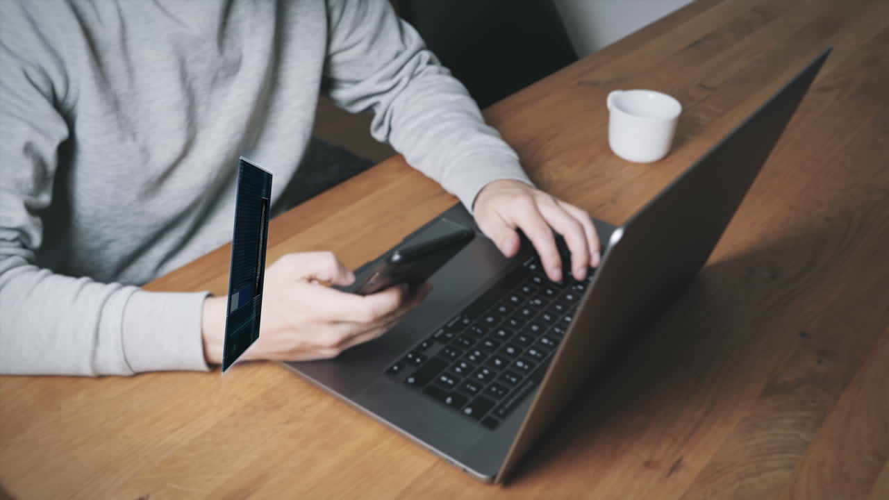 Young man at laptop pays internet shopping with digital credit card and verifies himself with fingerprint scan