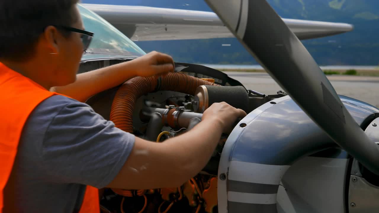 Mechanic lifting cowling and inspecting engine while circuit and padlock icon highlighting security