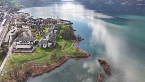 Eingebettet-Am-Walensee-In-Der-Schweiz-Säumt-Ein-Wohnviertel-Die-Uferlinie,-Während-Sich-Eisenbahnschienen-Durch-Die-Malerische-Dorfsiedlung-Murg-Schlängeln