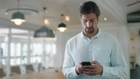 Atractivo-Joven-Hombre-De-Negocios-Usando-Un-Teléfono-Inteligente-En-La-Oficina-Enviando-Mensajes-De-Texto-Enviando-Correos-Electrónicos-Planeando-Reuniones-En-Red-Navegando-Mensajes-En-Tecnología-De-Telefonía-Móvil-4k