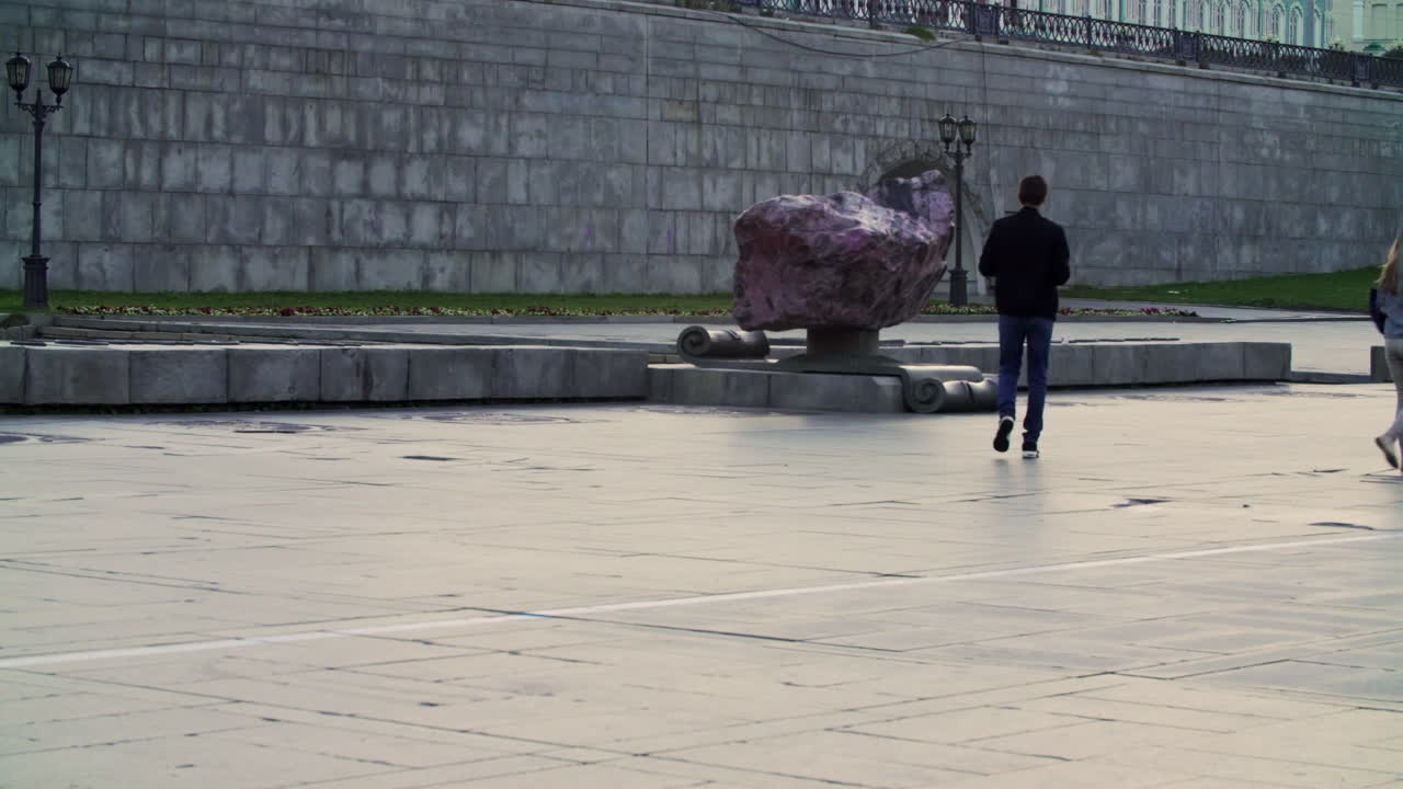 personas caminando en una plaza de la ciudad por un monumento