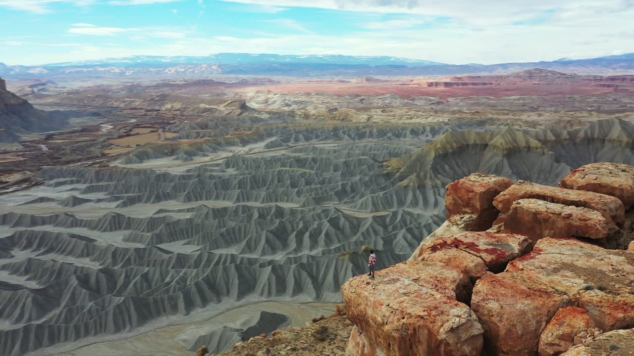 вид с воздуха, человек стоит на вершине мезы северный кейневиль над пропастью и пустынным ландшафтом штата юта, сша, съемка с орбитального беспилотника