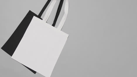 close up of white and black bags on grey background, with copy space, slow motion